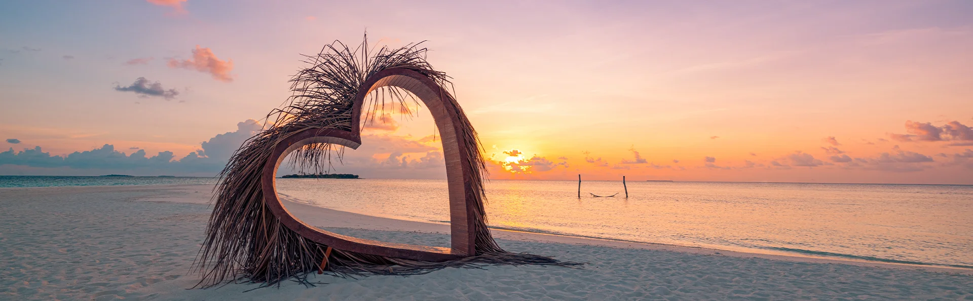 Heart sculpture on a tropical beach at sunset