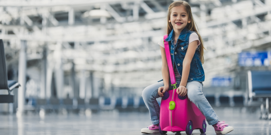 Child sitting on a suitcase in an airport