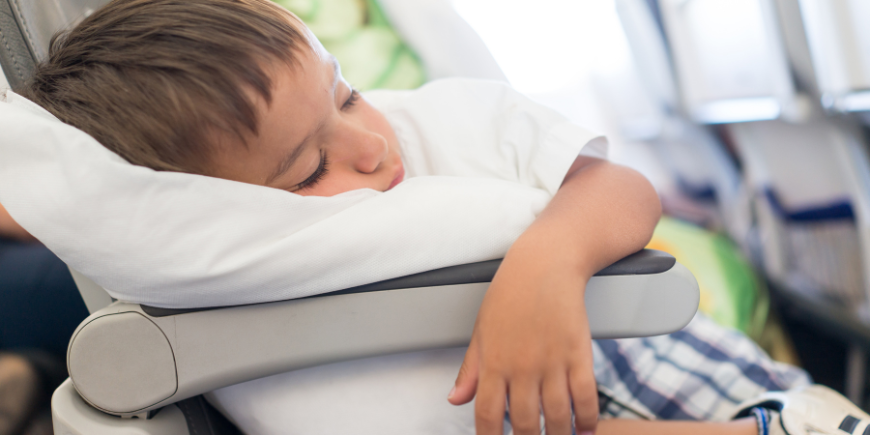 Boy sleeping with pillow in aeroplane