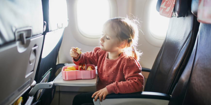 Child eating snacks on seat in aeroplane