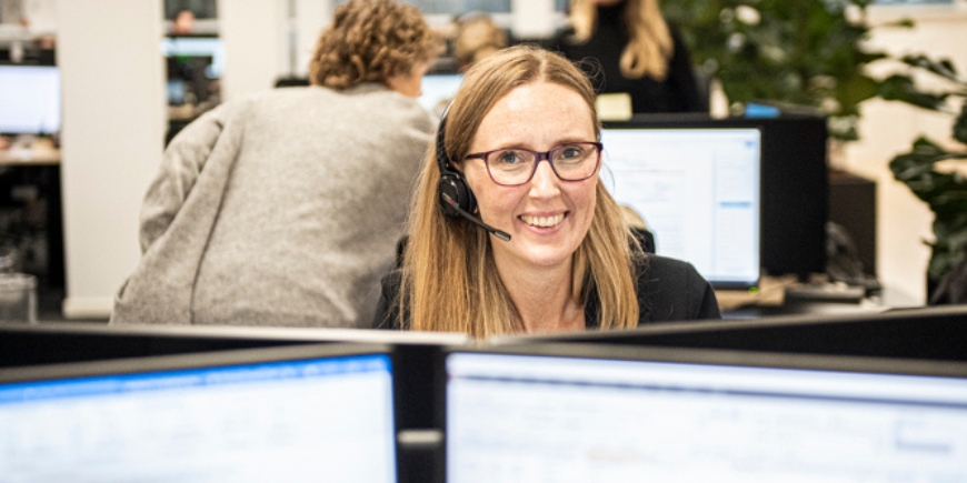 Travel specialist with headset works on support hotline in modern office