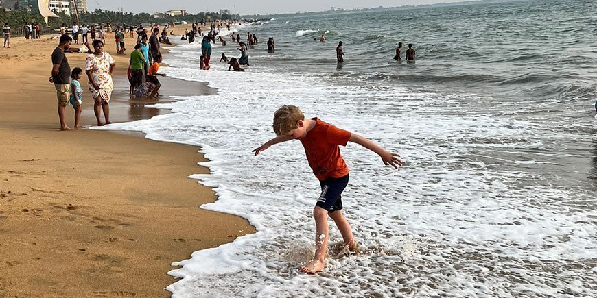 Boy walking at the water’s edge on a golden beach in Sri Lanka
