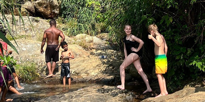 Children swimming in water by rocks