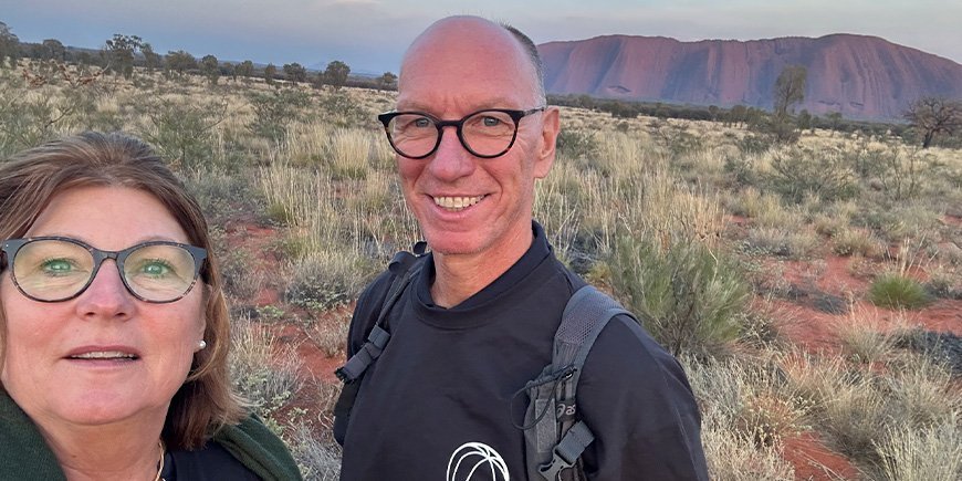 Beate and her husband take a photo in front of Uluru in Australia