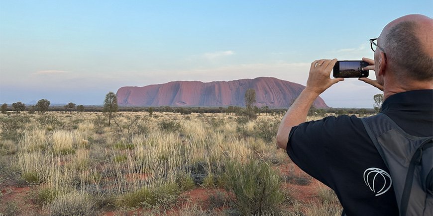 A man takes a picture of Uluru in Australia