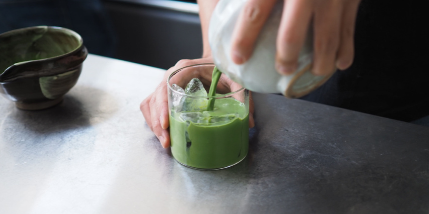 Person pouring matcha tea into glass