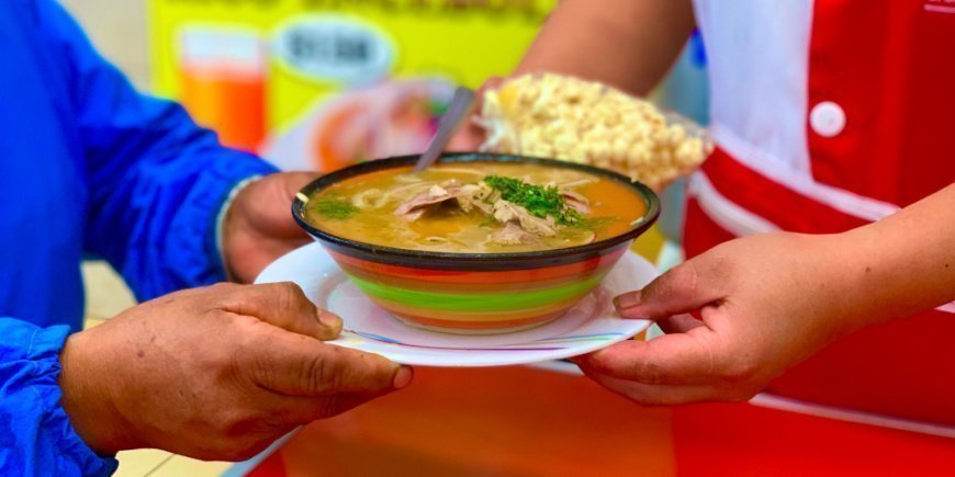Two people holding a bowl of encebollado