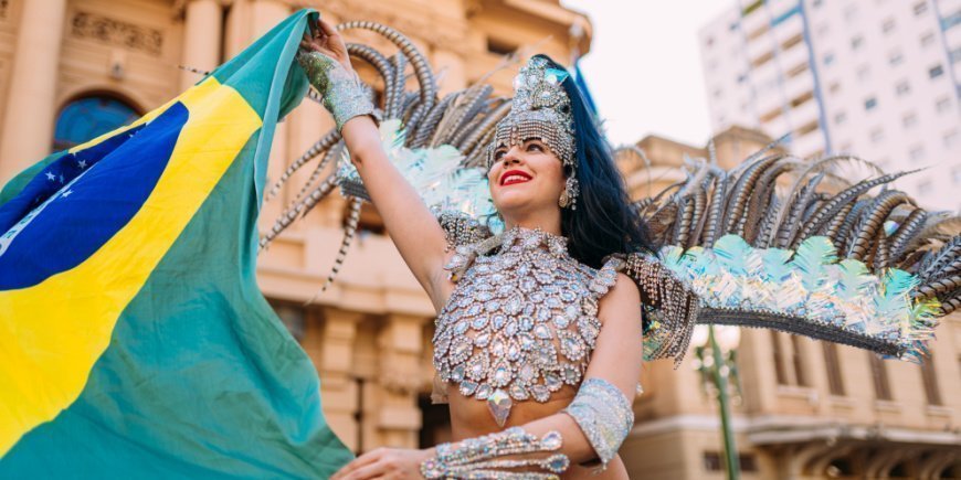 Brazilian woman dressed in colourful costume holding Brazilian flag