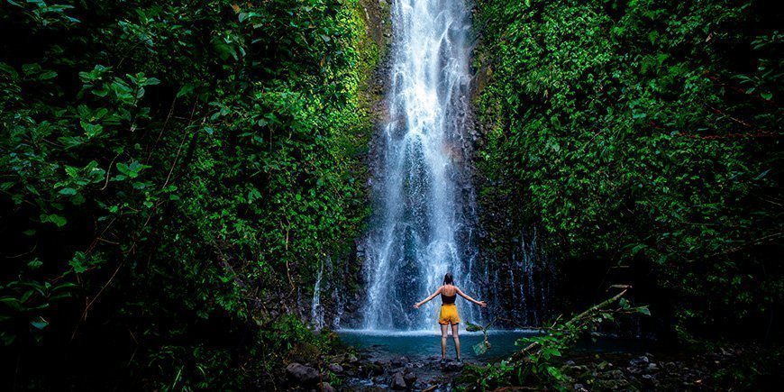 Woman standing in front of a waterfall in Costa Rica