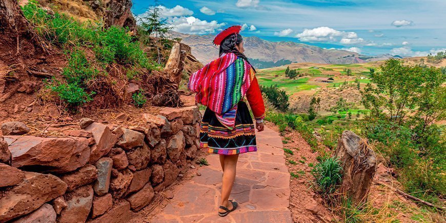 Indigenous woman walking along an Inca wall in Cusco in October