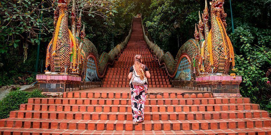 Woman climbing the stairs at Doi Suthep Temple in Chiang Mai, Thailand.