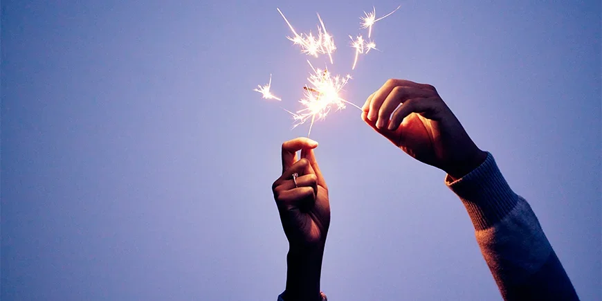 A man’s and a woman’s hands holding sparklers
