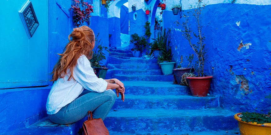 Woman sitting on stairs in the blue city of Chefchaouen, Morocco