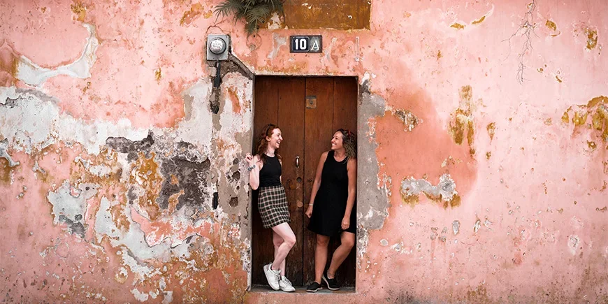 Two women standing in front of a colourful wall in Antigua, Guatemala