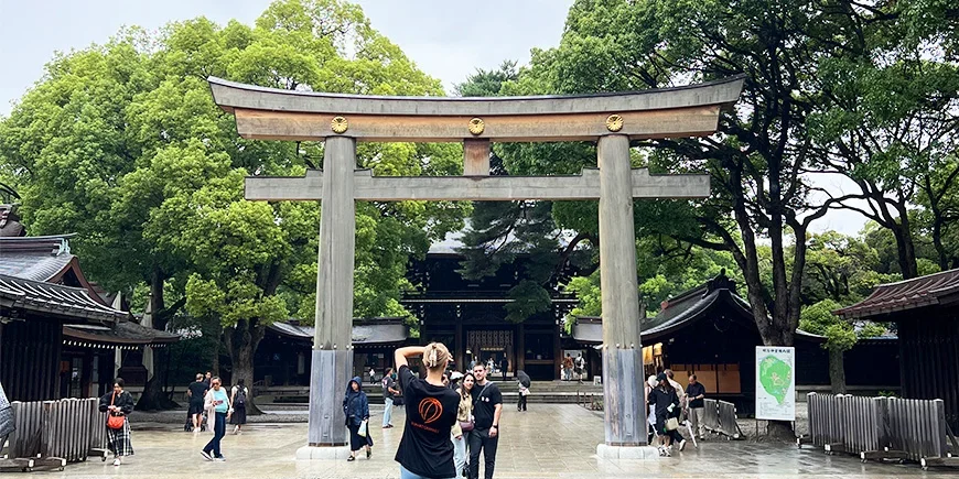 Woman taking a photo of a couple under a Torii gate at Meiji Shrine