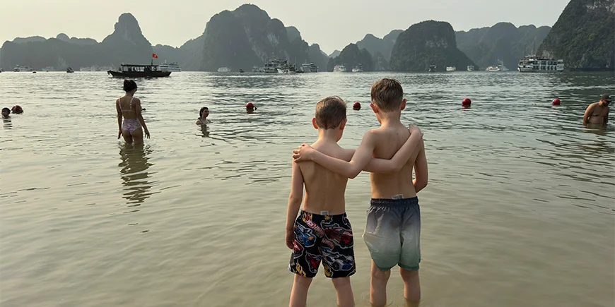 Two boys hugging each other on a beach in Halong Bay