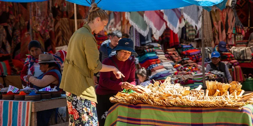 Woman talking to a local about the items she’s selling at a market in Cusco, Peru