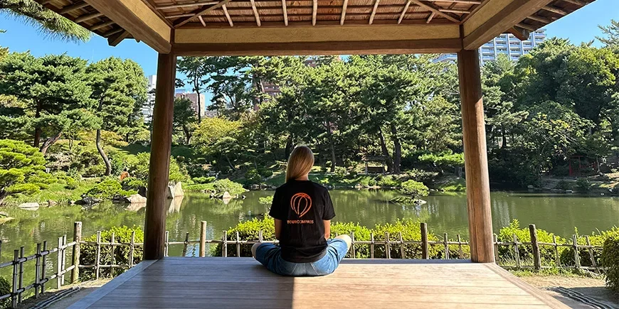 Woman in a TourCompass T-shirt in a beautiful Japanese garden in Hiroshima