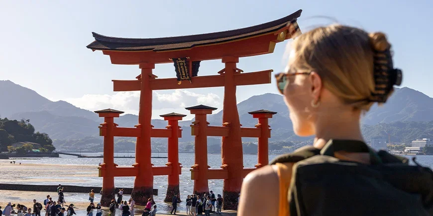 Woman looking at the red shrine on Miyajima Island in Hiroshima