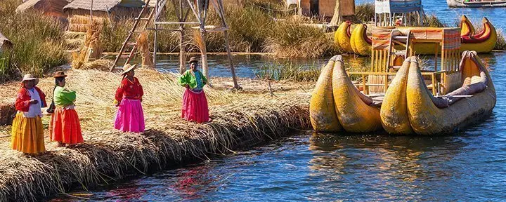 Peruvian women in traditional dress welcoming tourists to Uros Island