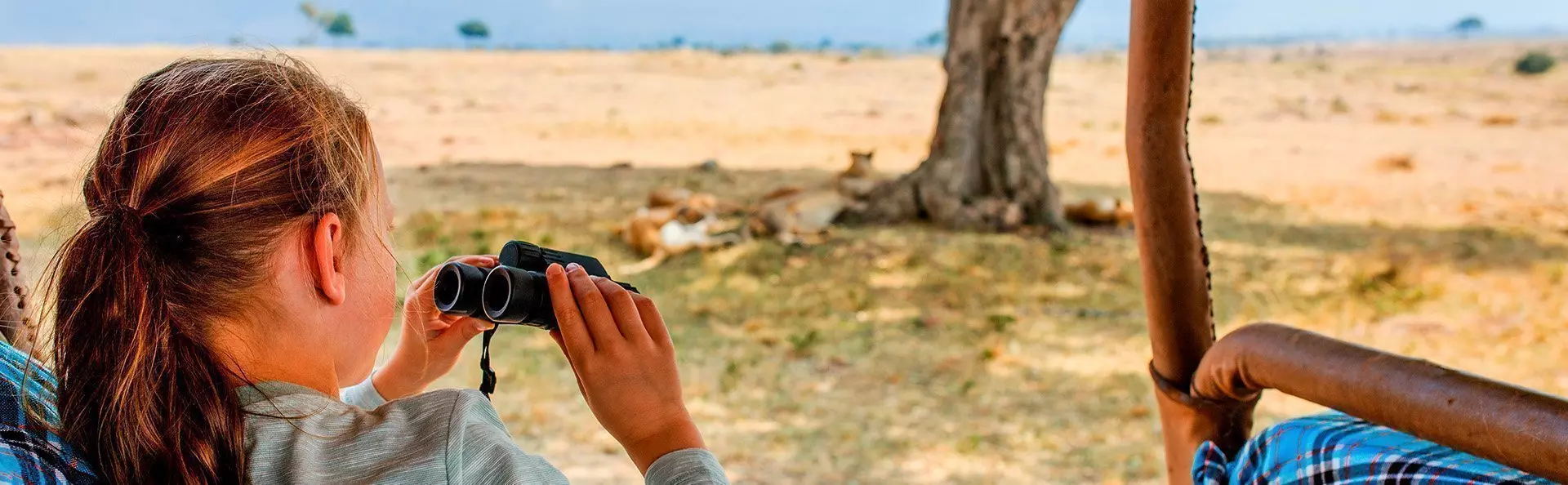 Girl on safari in Kenya with lions in the background.