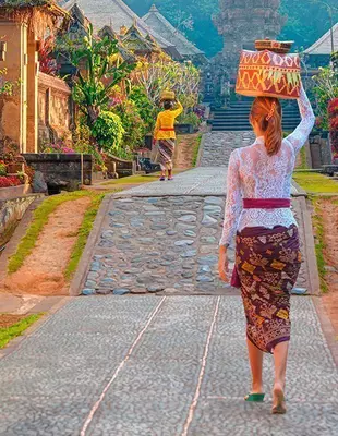 Woman walking with a basket on her head in Balinese village