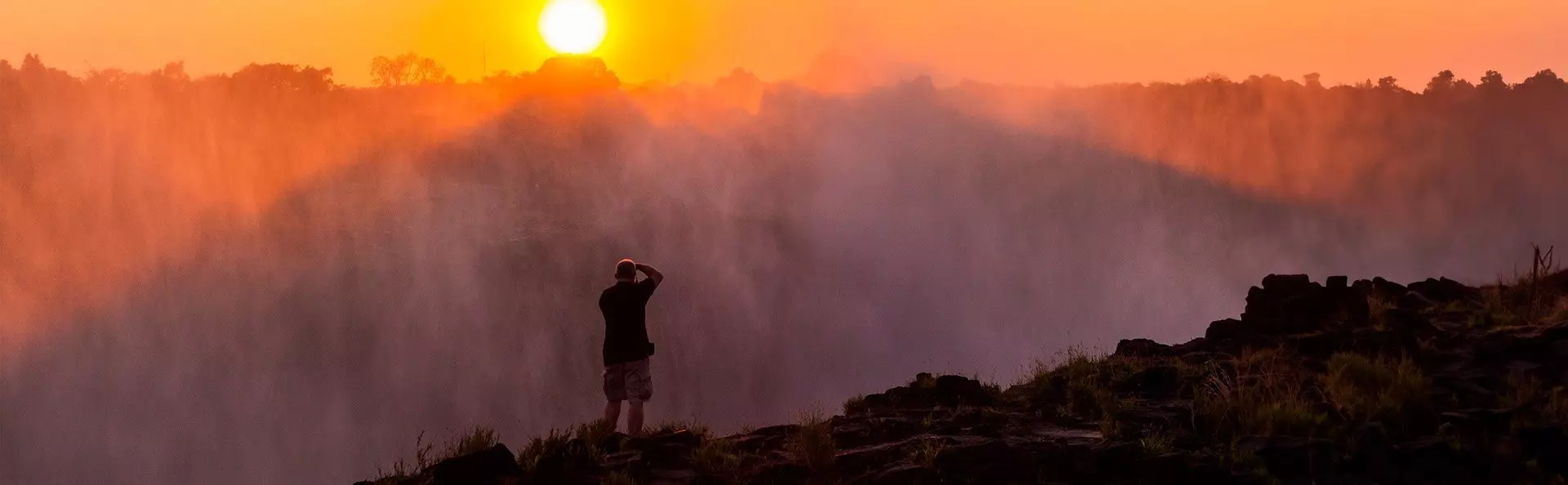 Man taking photos of Victoria Falls at dusk