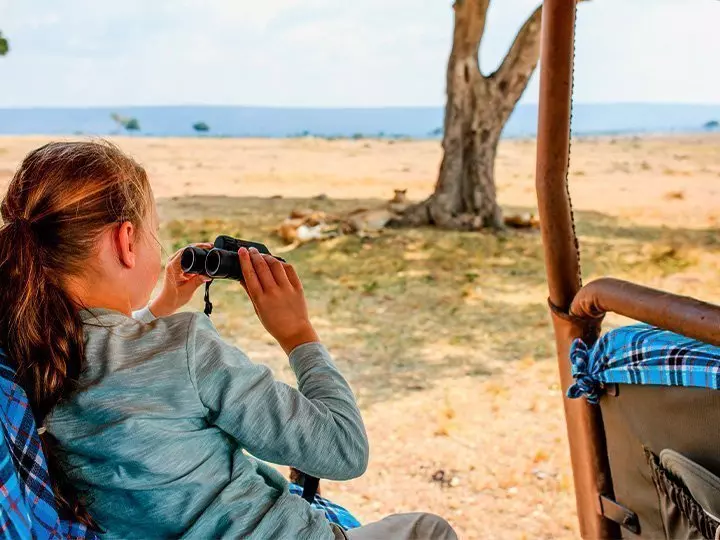 Girl on safari in Kenya with lions in the background.