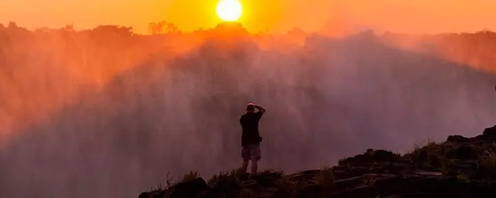 Man taking photos of Victoria Falls at dusk