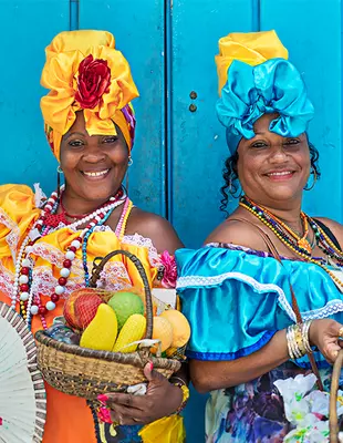 Portrait of happy Cuban women leaning against a blue wooden wall.